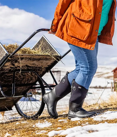 Person pulling hay cart wearing Bogs