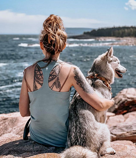 Woman sitting on rocky coast with dog