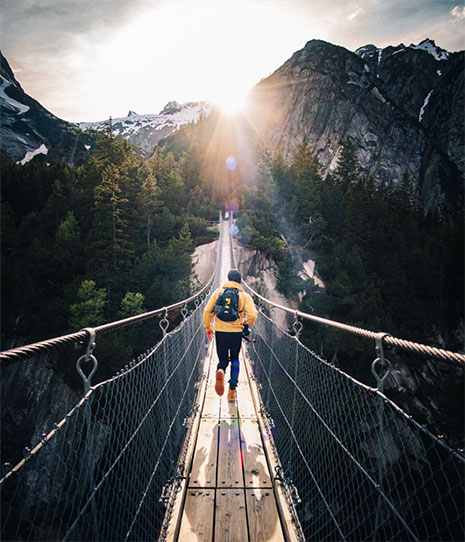 Person hiking across suspended bridge